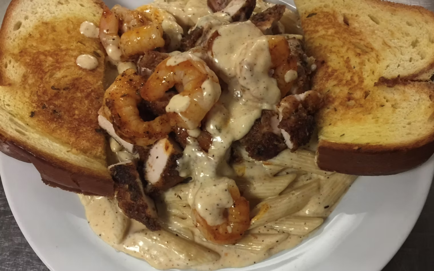 Plate of creamy pasta with shrimp, sausage, and toasted bread.