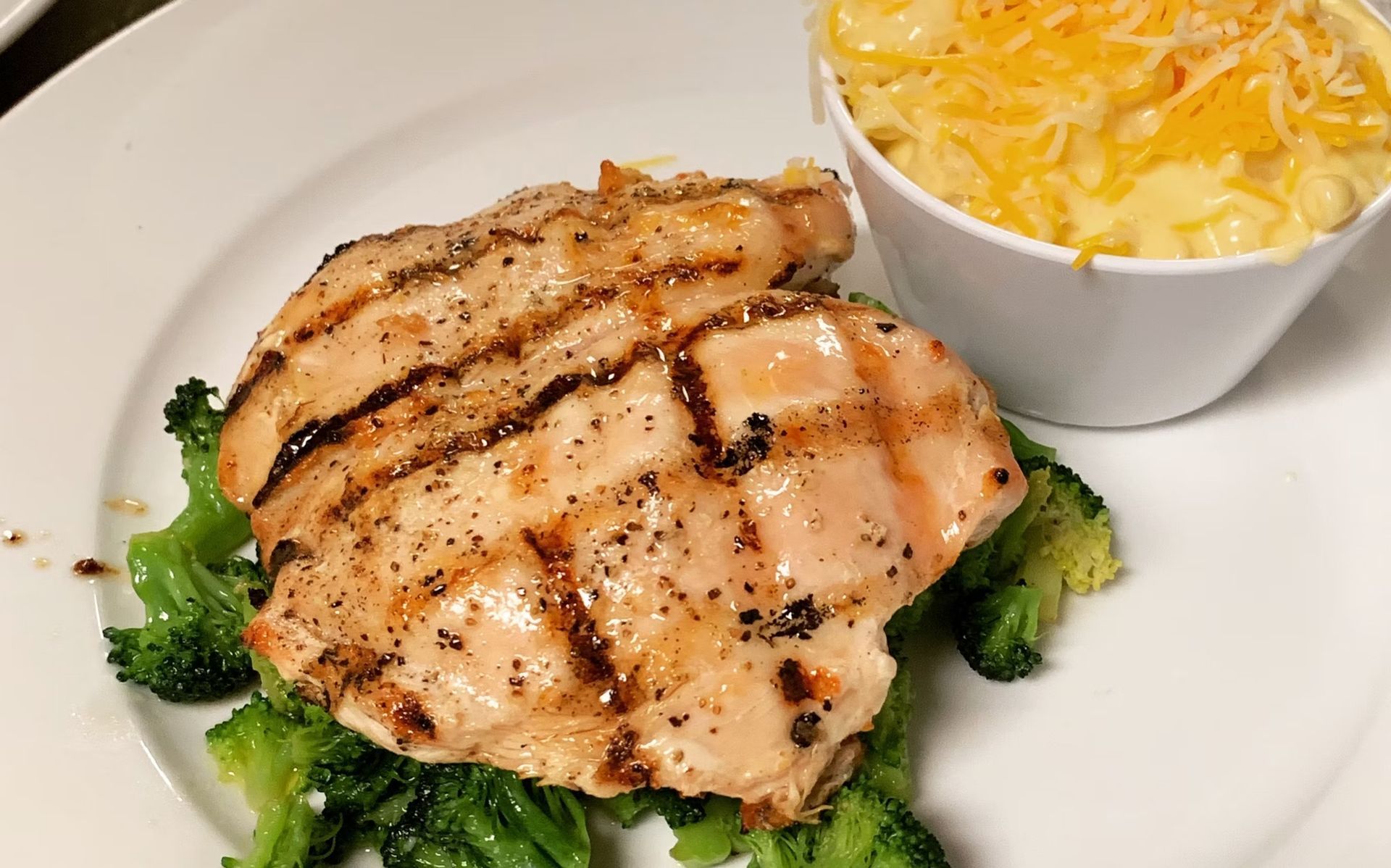 Grilled chicken breast on broccoli with mac and cheese.
