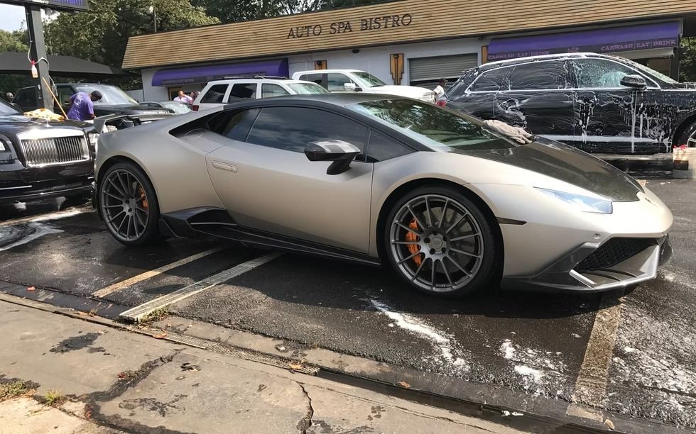 A silver Lamborghini being washed at a car wash.