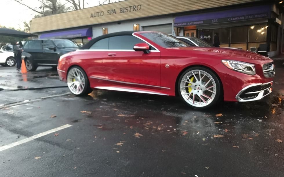 Red convertible car parked outside a building, wet pavement.
