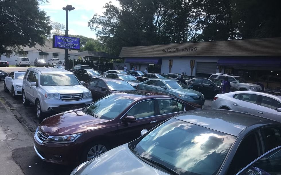 Cars parked at a car dealership with a sign in the background that says 
