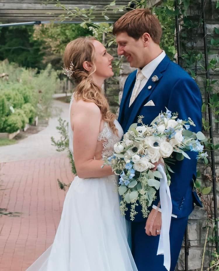 A bride and groom are standing next to each other holding a bouquet of flowers.