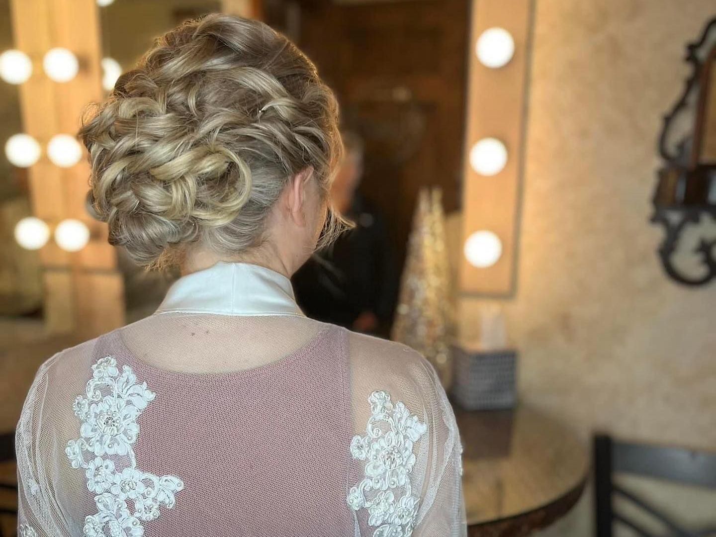 A woman is getting her hair done in front of a mirror.