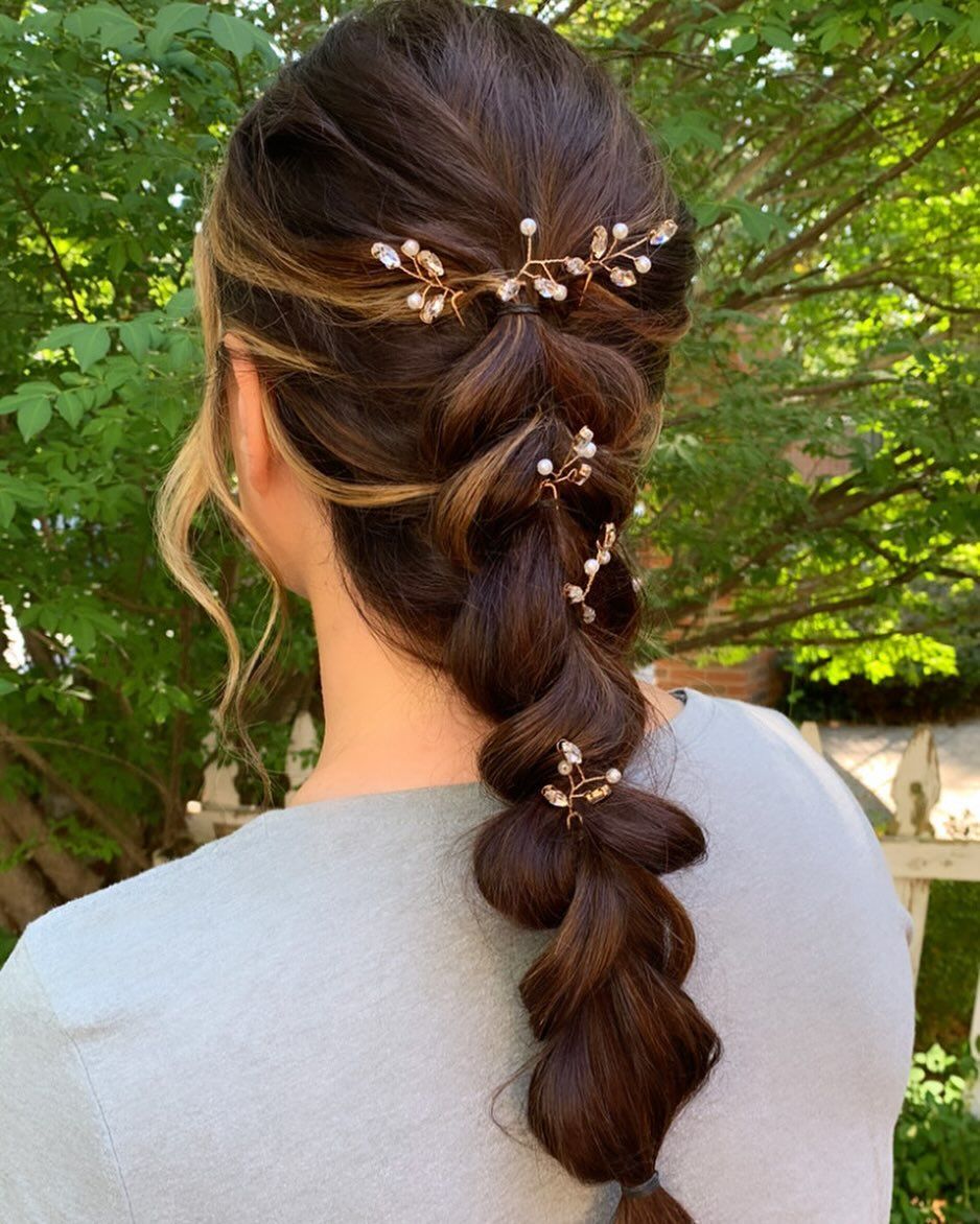A woman is wearing a braided hairstyle with pearls in her hair.