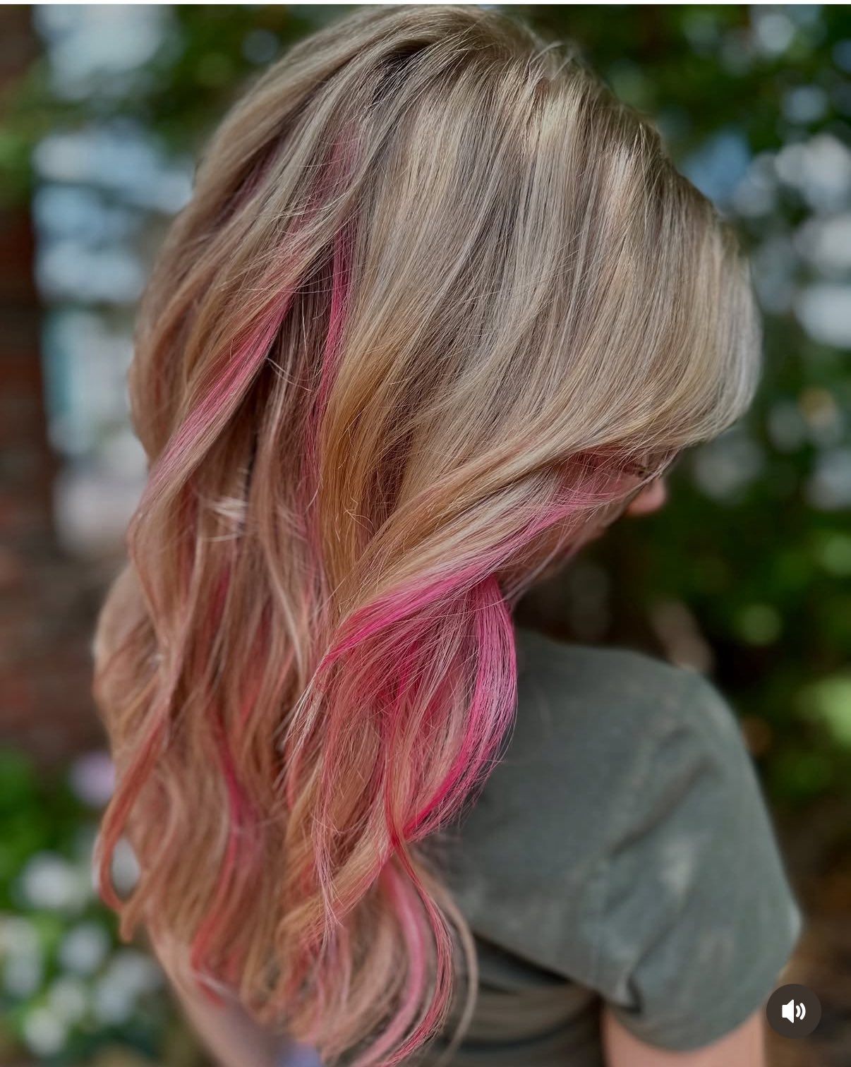 Woman with long, wavy blonde hair with pink highlights.