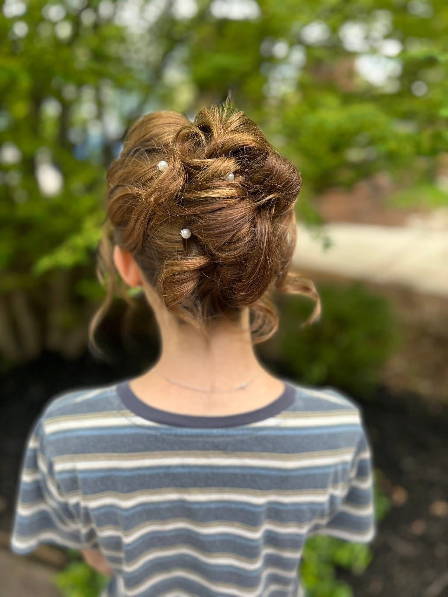 Back view of a child with messy hair in a striped shirt, standing outdoors on a path.