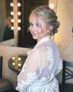A woman in a white robe is standing in front of a mirror.
