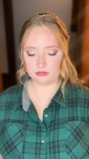 A woman wearing a green plaid shirt with her eyes closed.