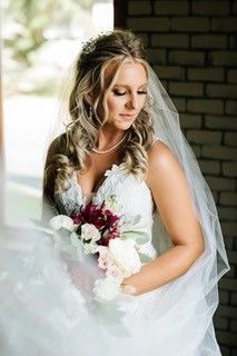 The bride is wearing a veil and holding a bouquet of flowers.