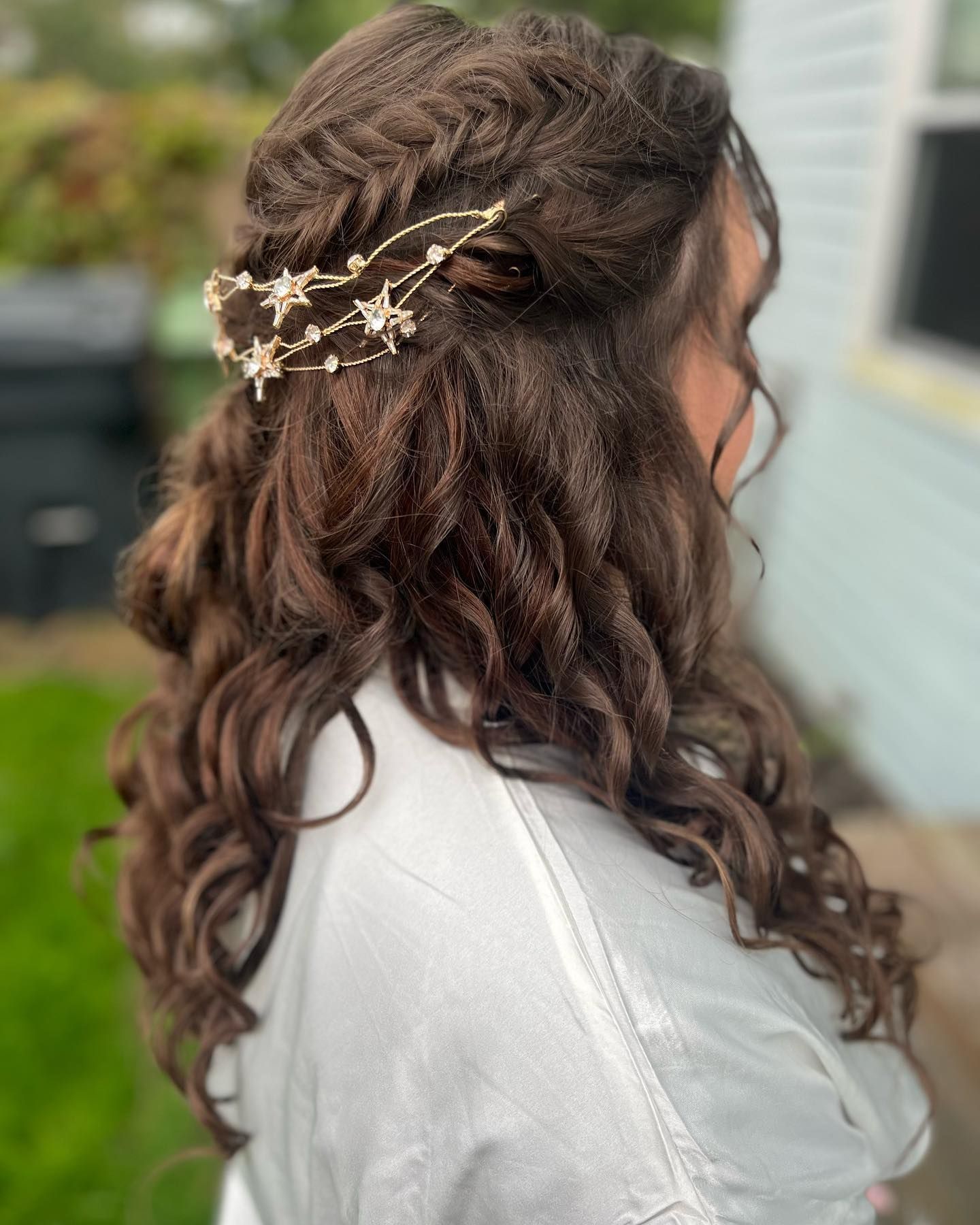 A woman with long brown hair is wearing a braided half up half down hairstyle.
