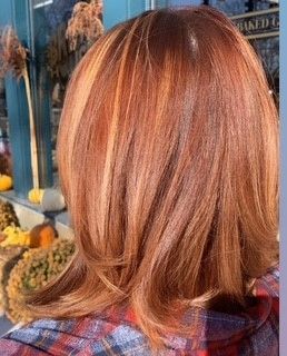 The back of a woman's head with red hair and a plaid shirt.