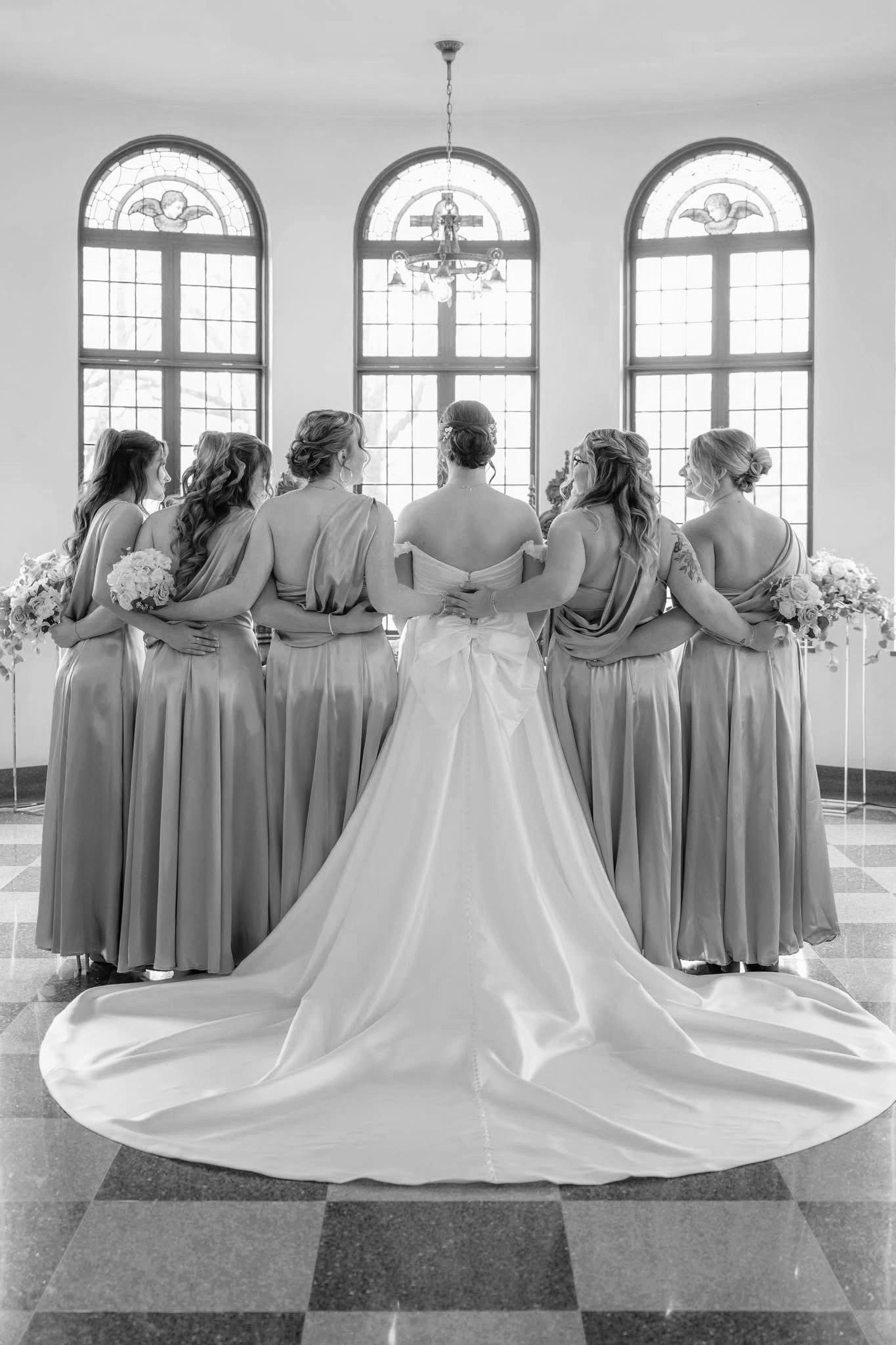 A bride and her bridesmaids are posing for a black and white photo.