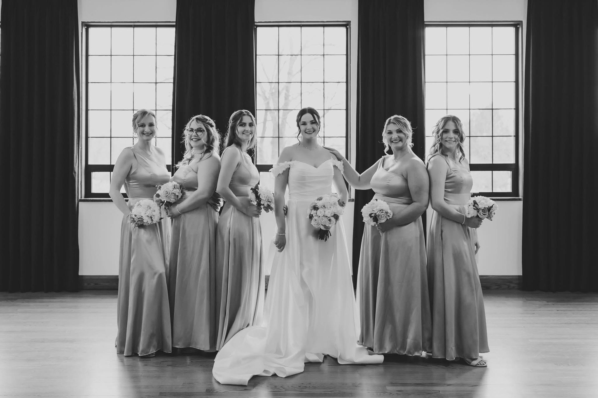 A bride and her bridesmaids are posing for a black and white photo.