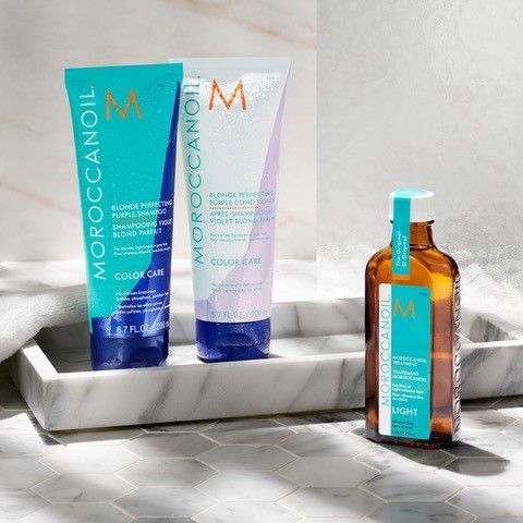 Three bottles of Moroccan Oil hair products are sitting on a marble tray.