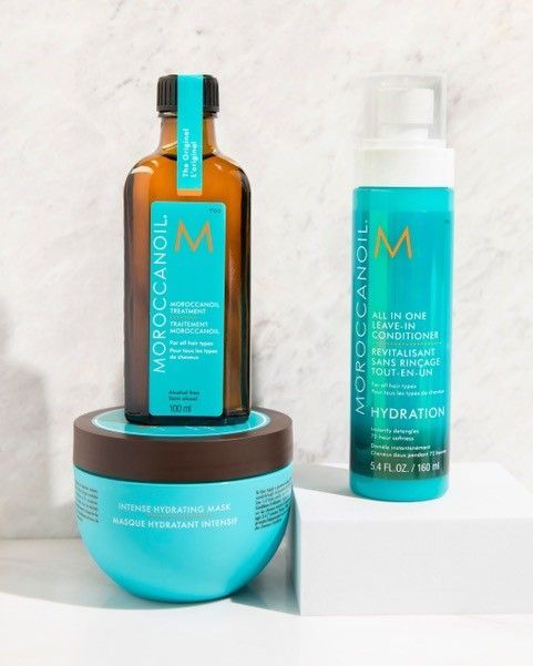 Three bottles of Moroccan Oil hair products are sitting on a table