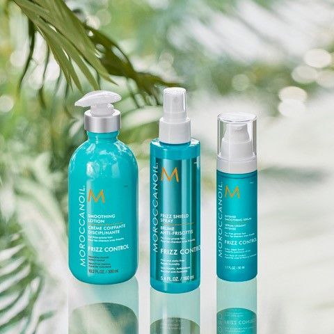 Three bottles of Moroccan Oil hair products are sitting next to each other on a table.