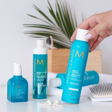 A person is holding a bottle of Moroccan Oil product