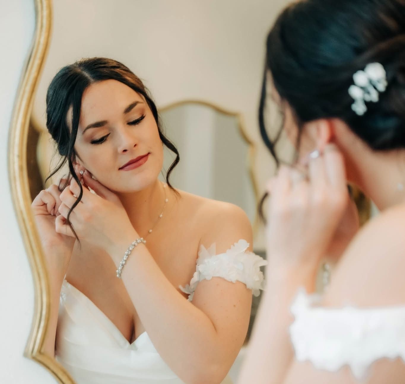 A woman in a white dress is looking at herself in a mirror