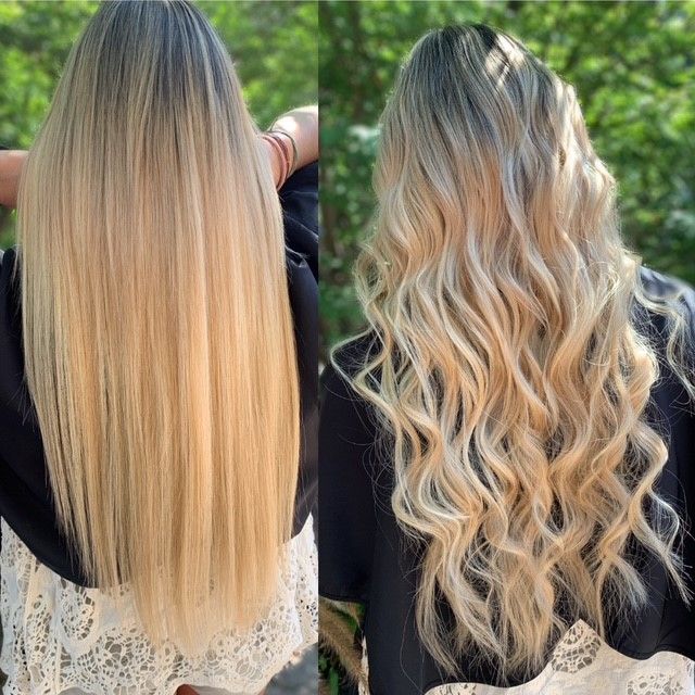 A woman with long blonde hair is standing in front of trees.