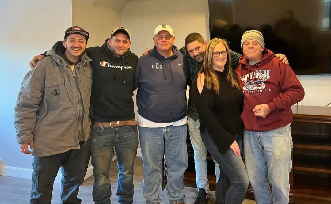 A group of people are posing for a picture together in a living room.