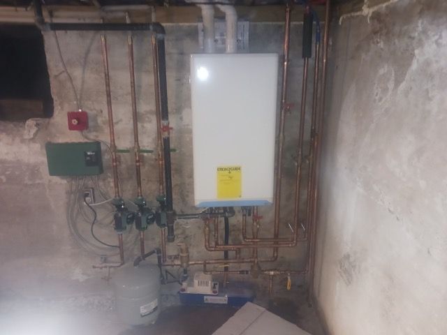 A water heater is sitting in a basement next to a wall.