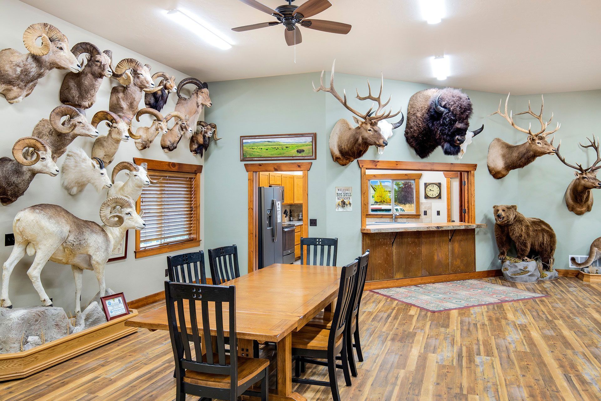 A dining room with a table and chairs and stuffed animals on the wall.