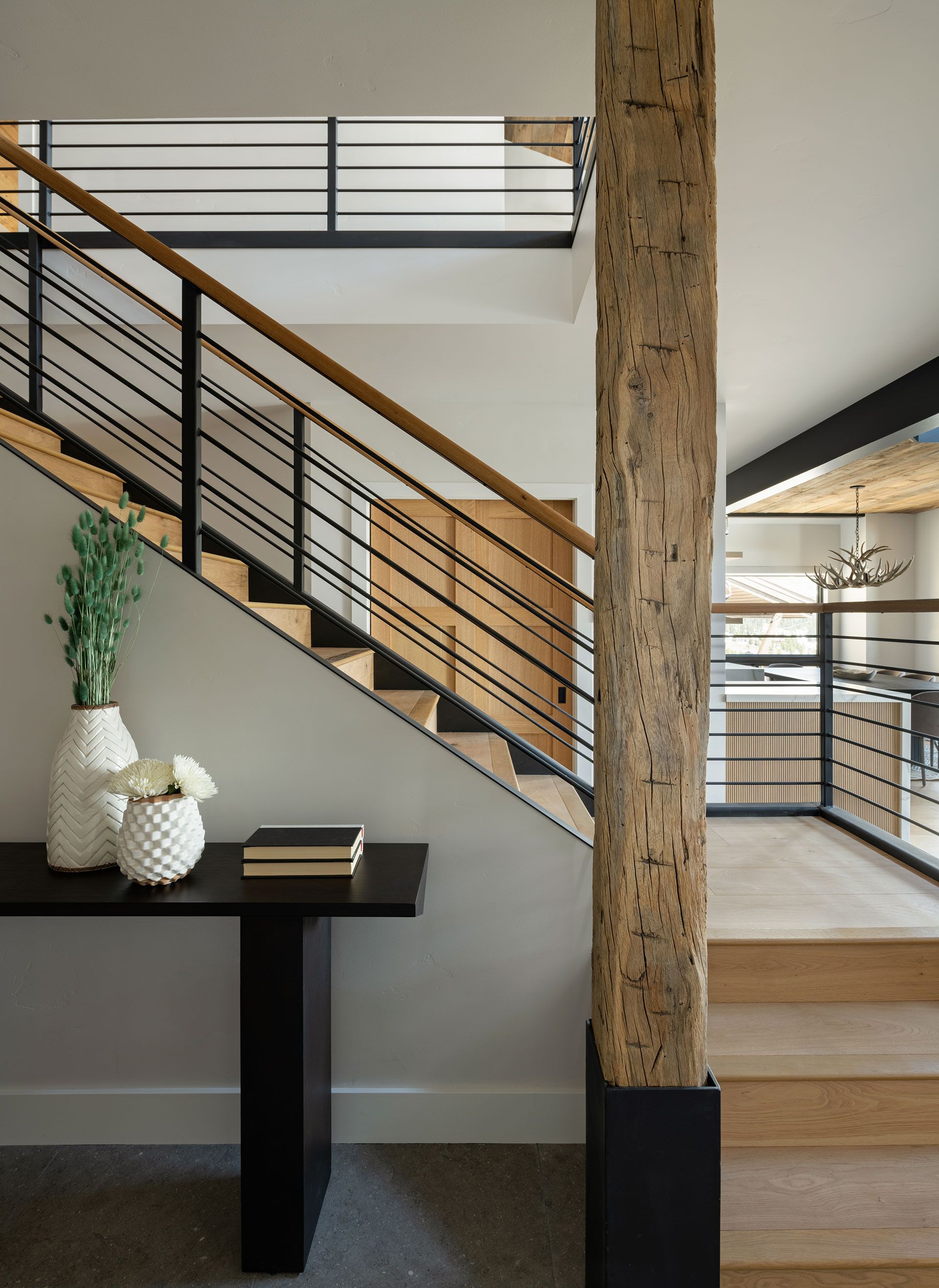 A wooden staircase with a metal railing and a wooden post