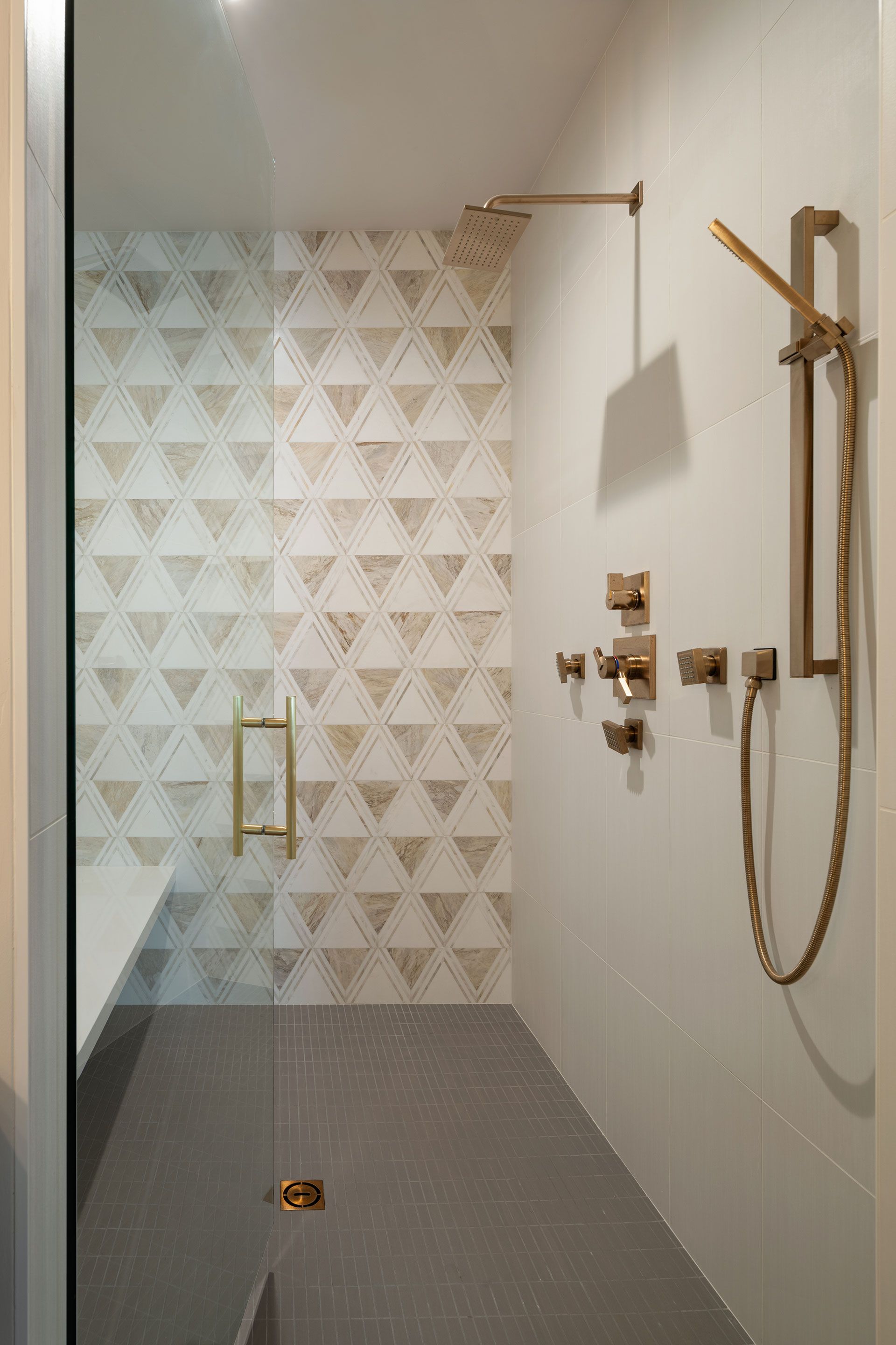 A bathroom with a walk in shower with a geometric pattern on the wall