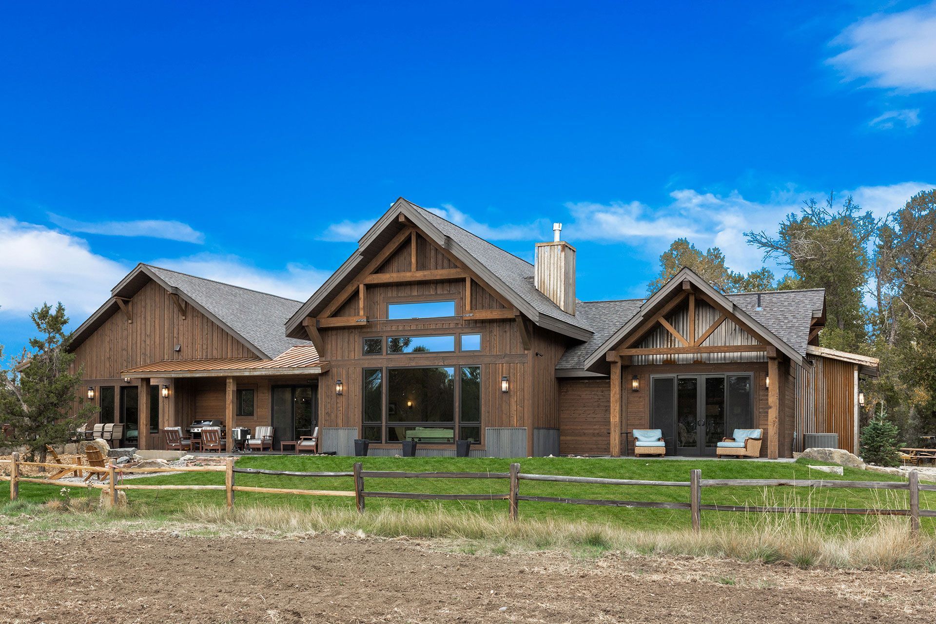 A large wooden house is sitting in the middle of a grassy field