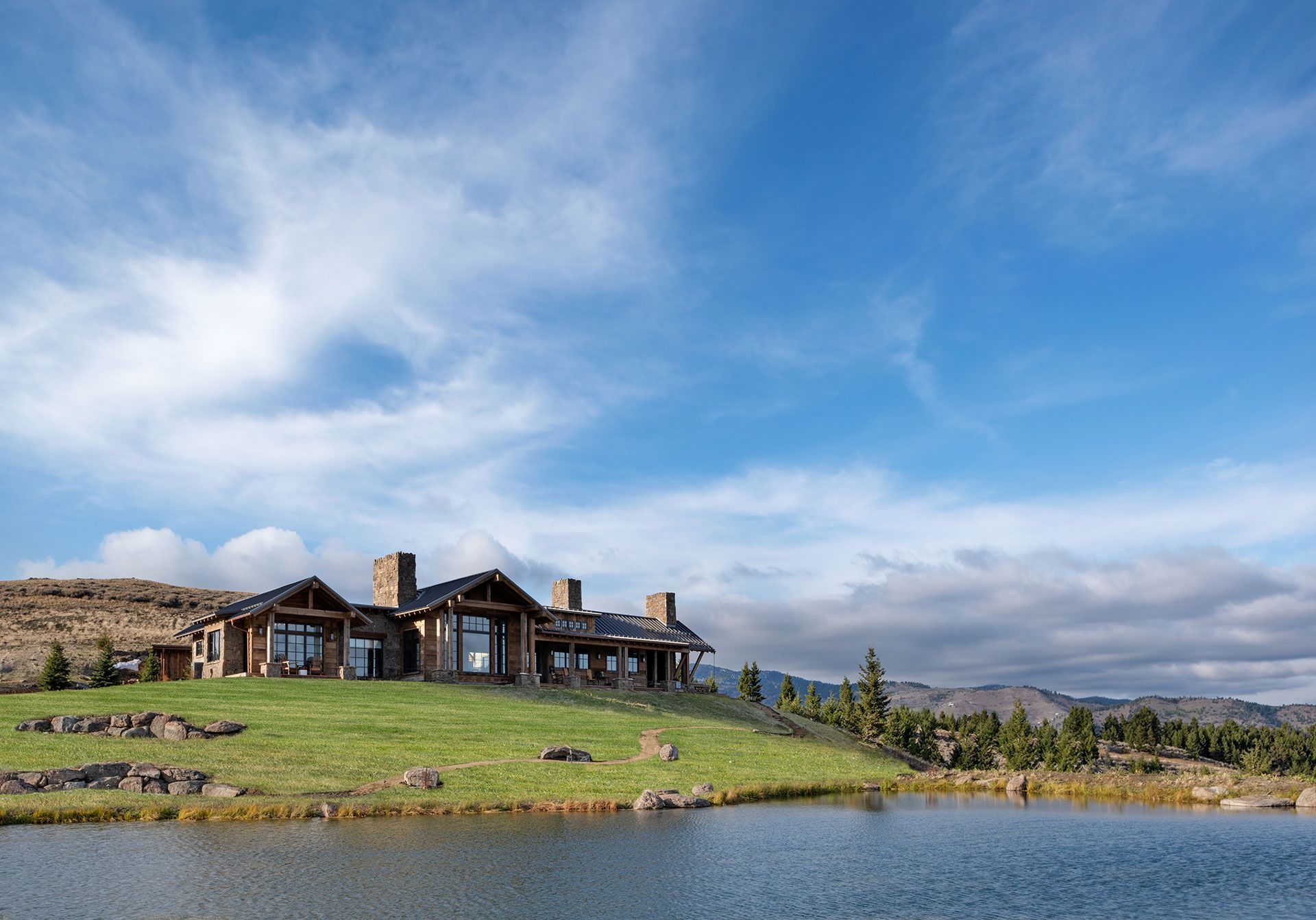 A large house is sitting on top of a hill next to a lake