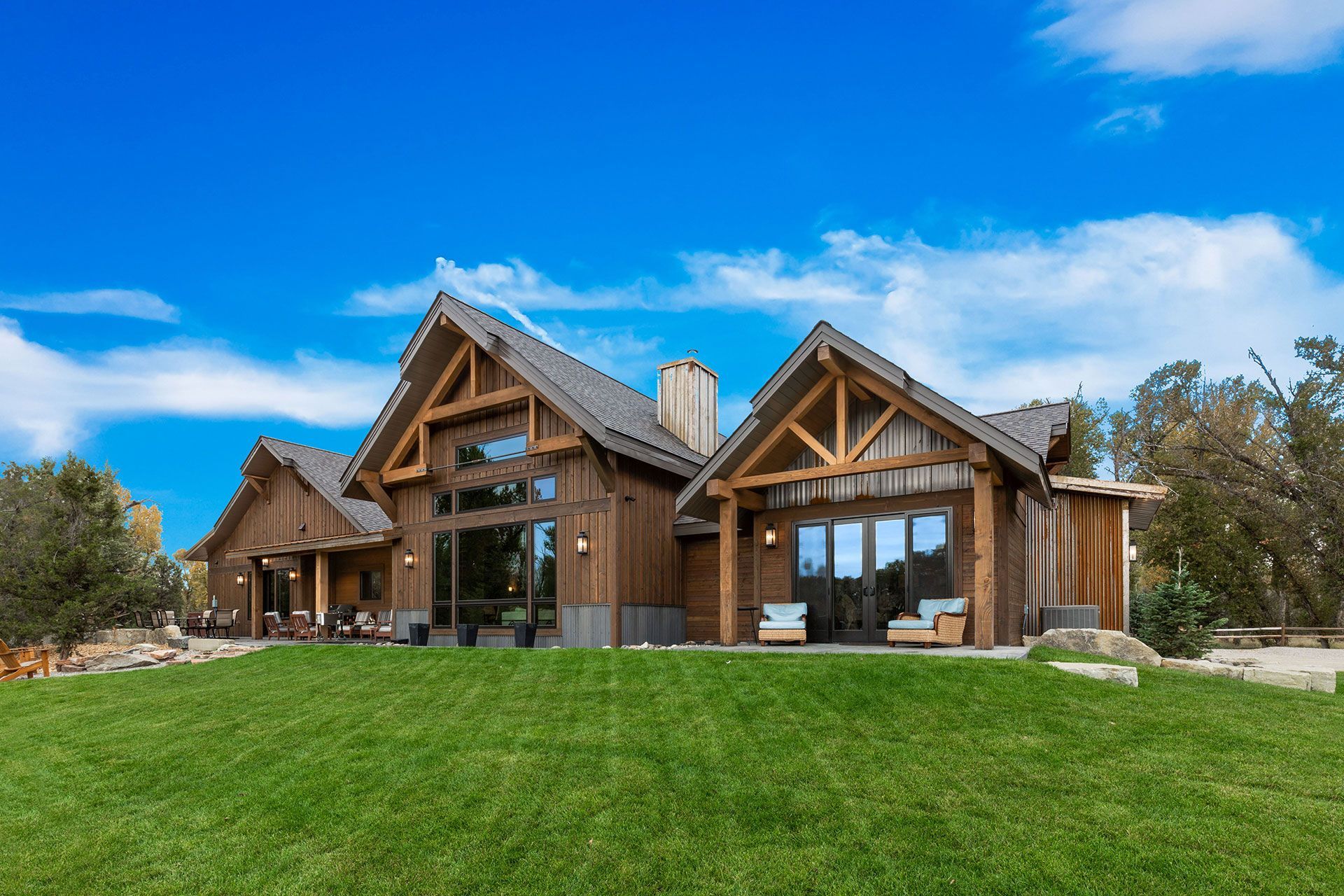 A large wooden house is sitting on top of a lush green field