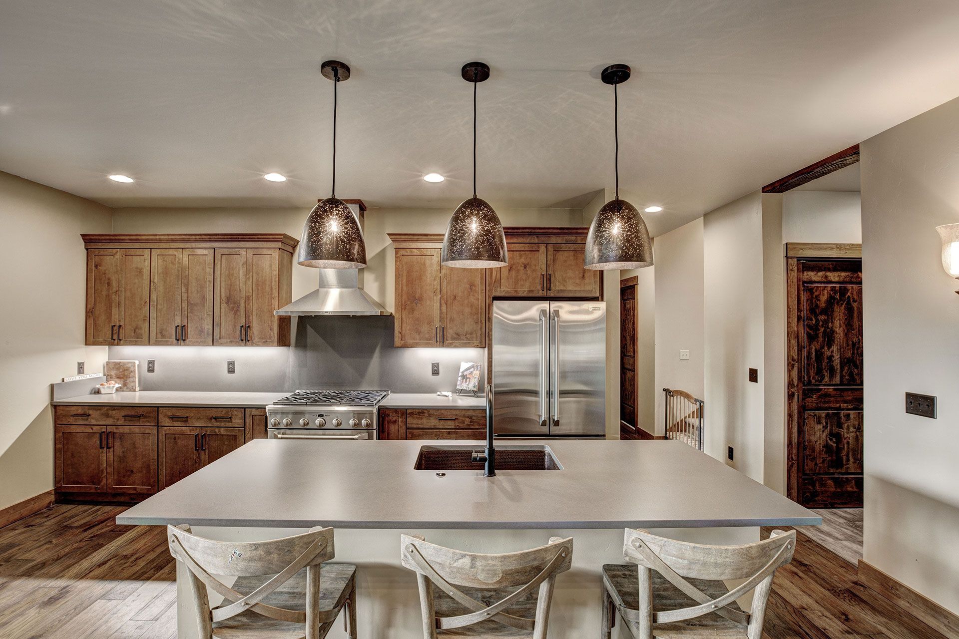 A kitchen with stainless steel appliances, wooden cabinets, a large island, and a sink