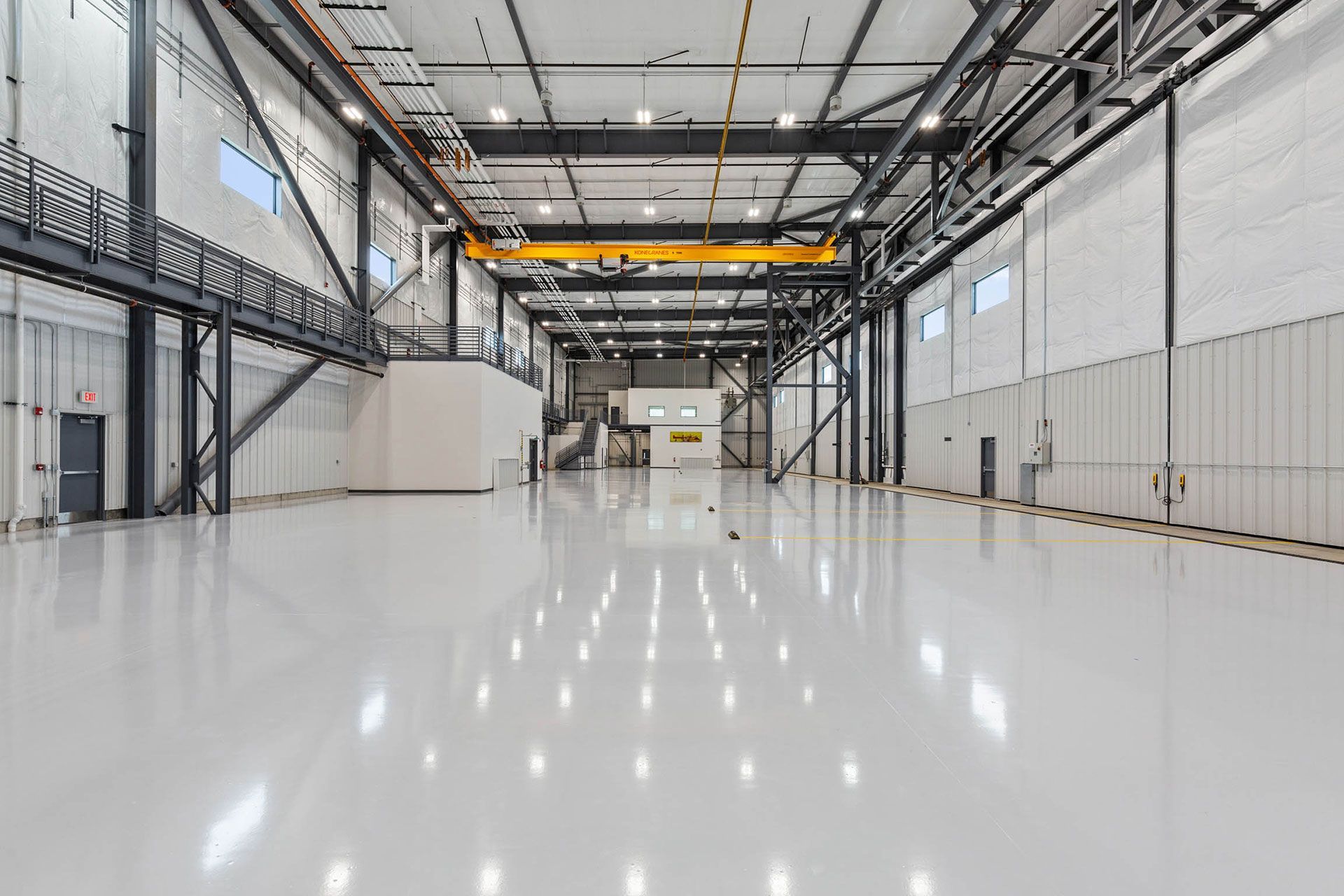 A large empty warehouse with a crane hanging from the ceiling