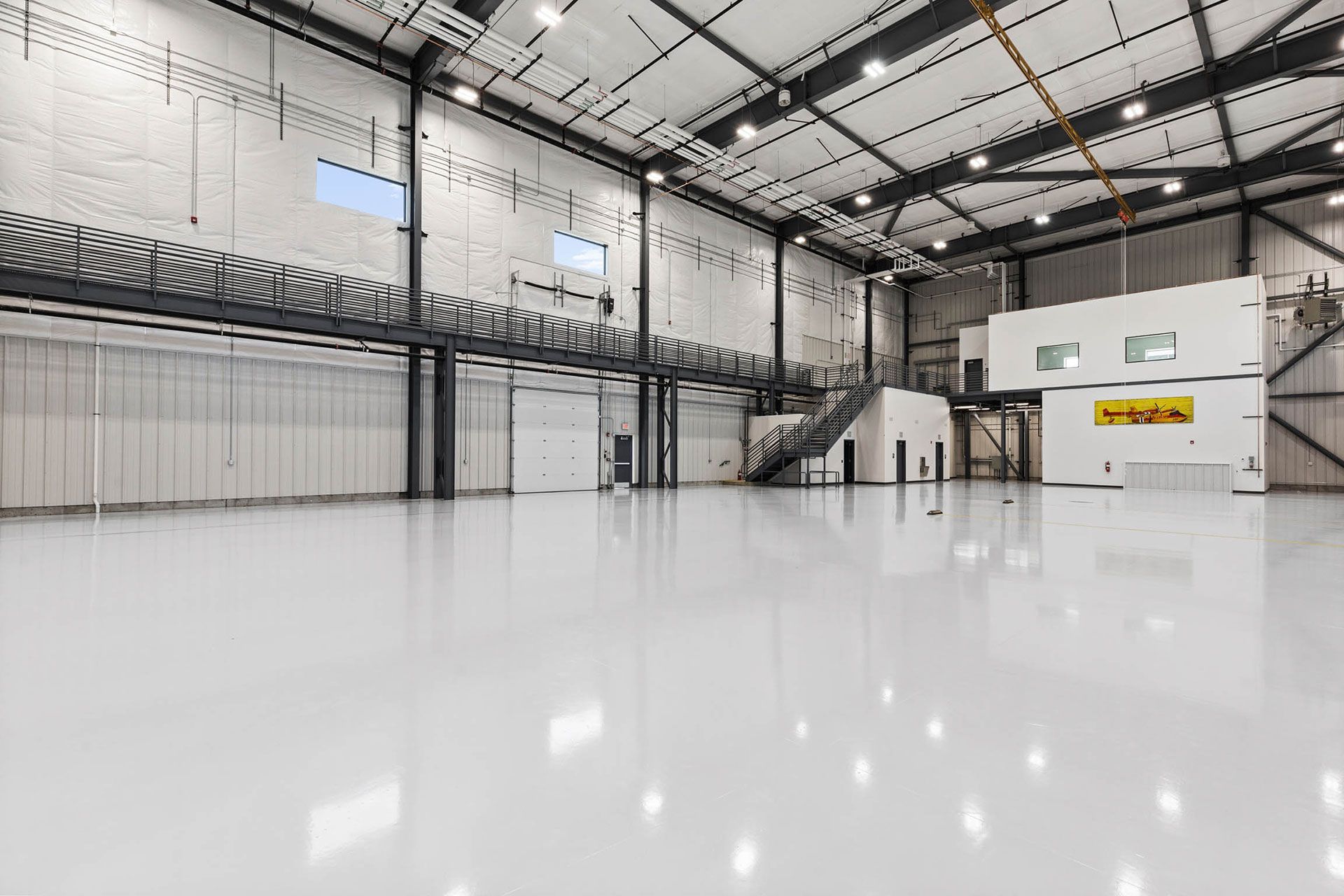 A large empty warehouse with a white floor and stairs