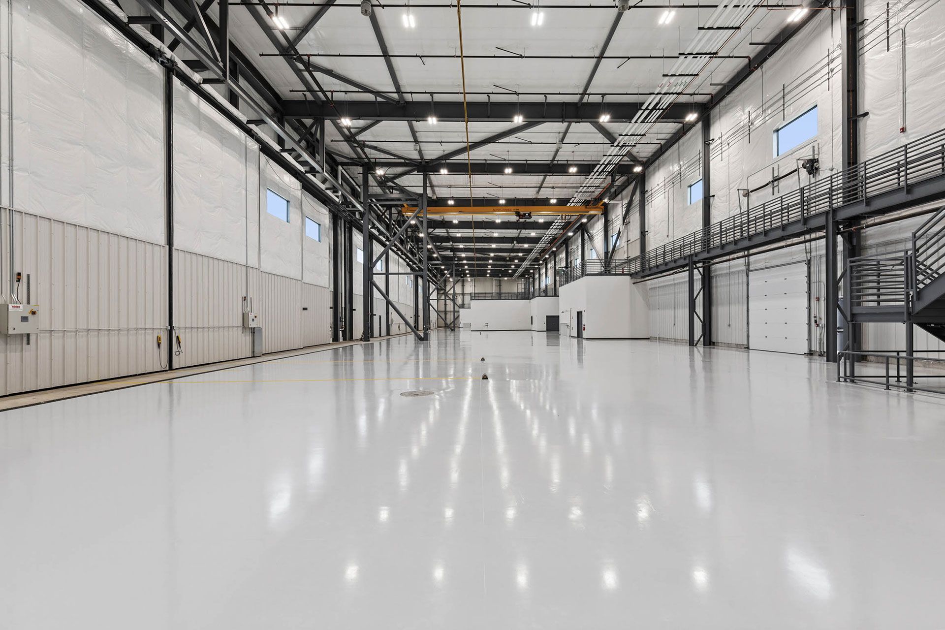 A large empty warehouse with a white floor and stairs