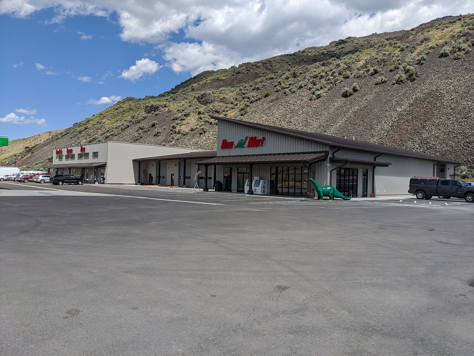 A store with a parking lot in front of it and a mountain in the background