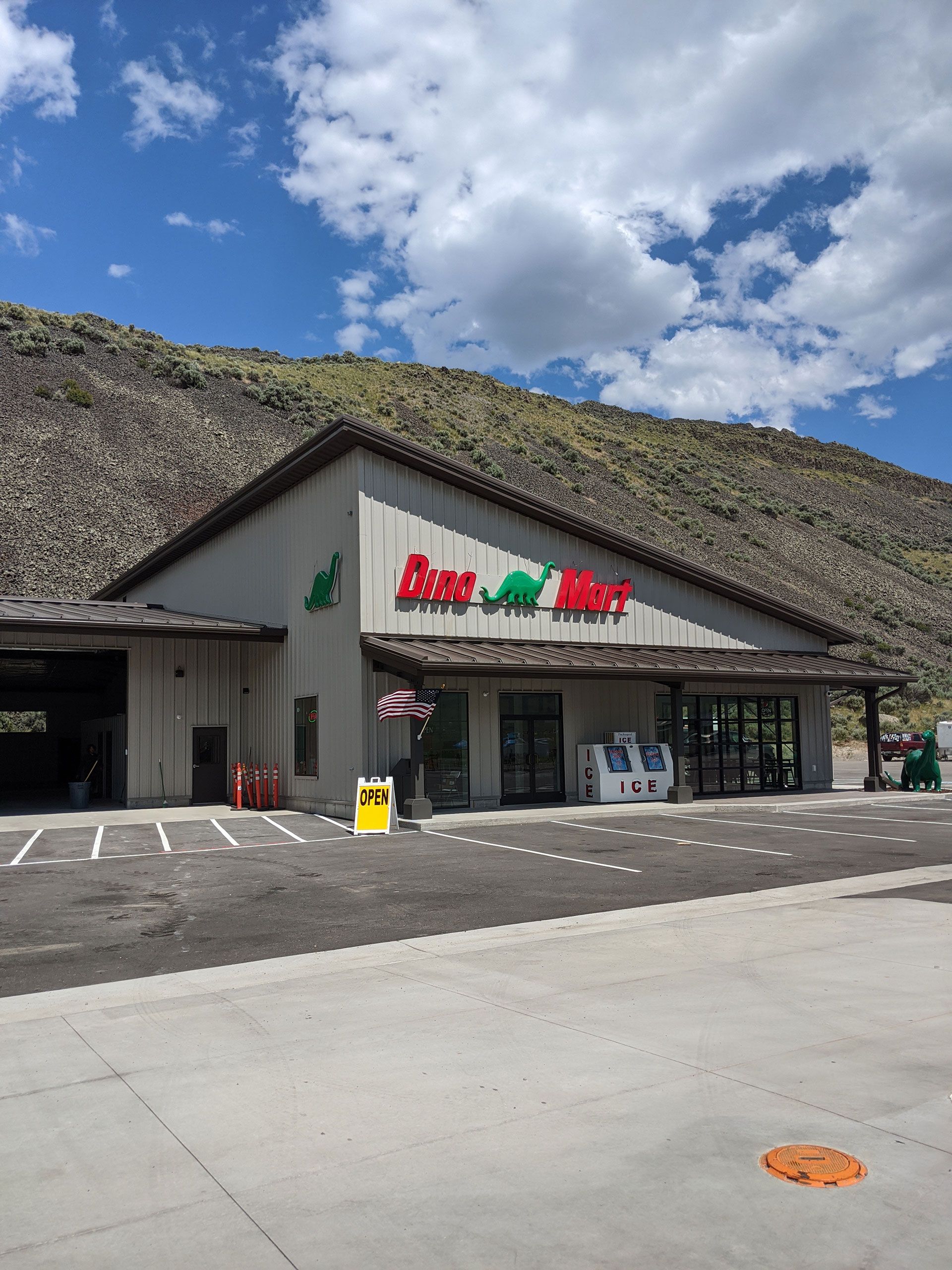 A gas station with mountains in the background and a parking lot in front of it