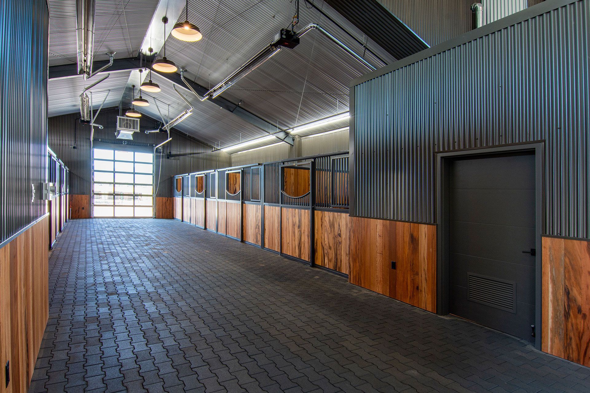 The inside of a horse barn with wooden walls and a brick floor