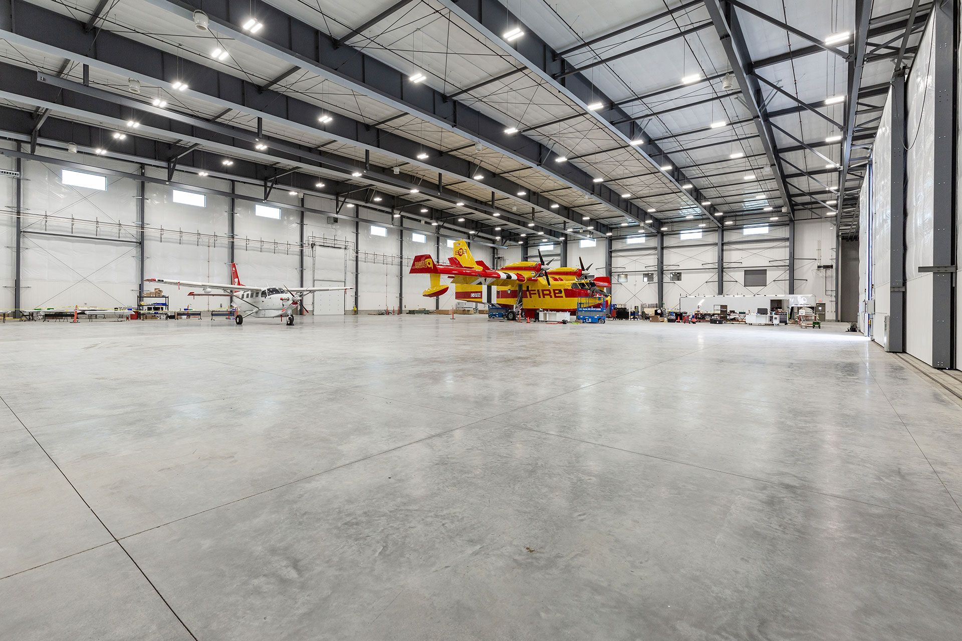 A large empty warehouse with a plane parked inside of it