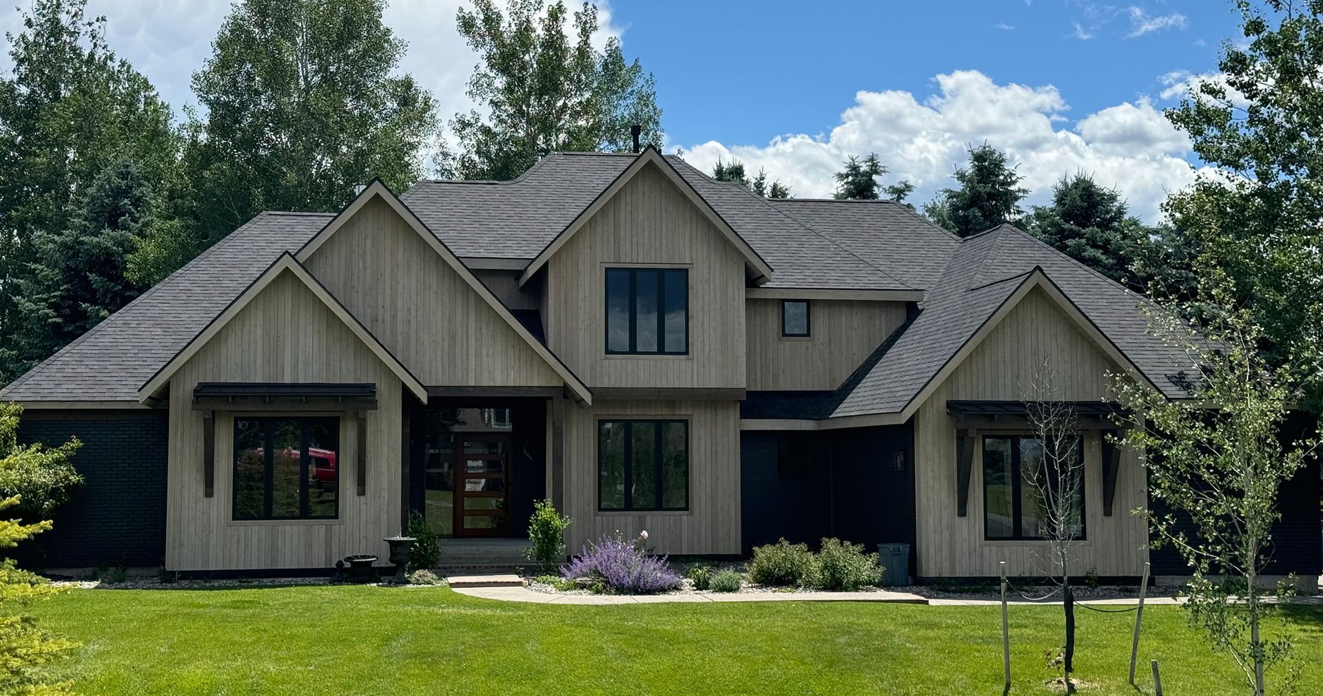 A large house with a lot of windows is surrounded by trees and grass.