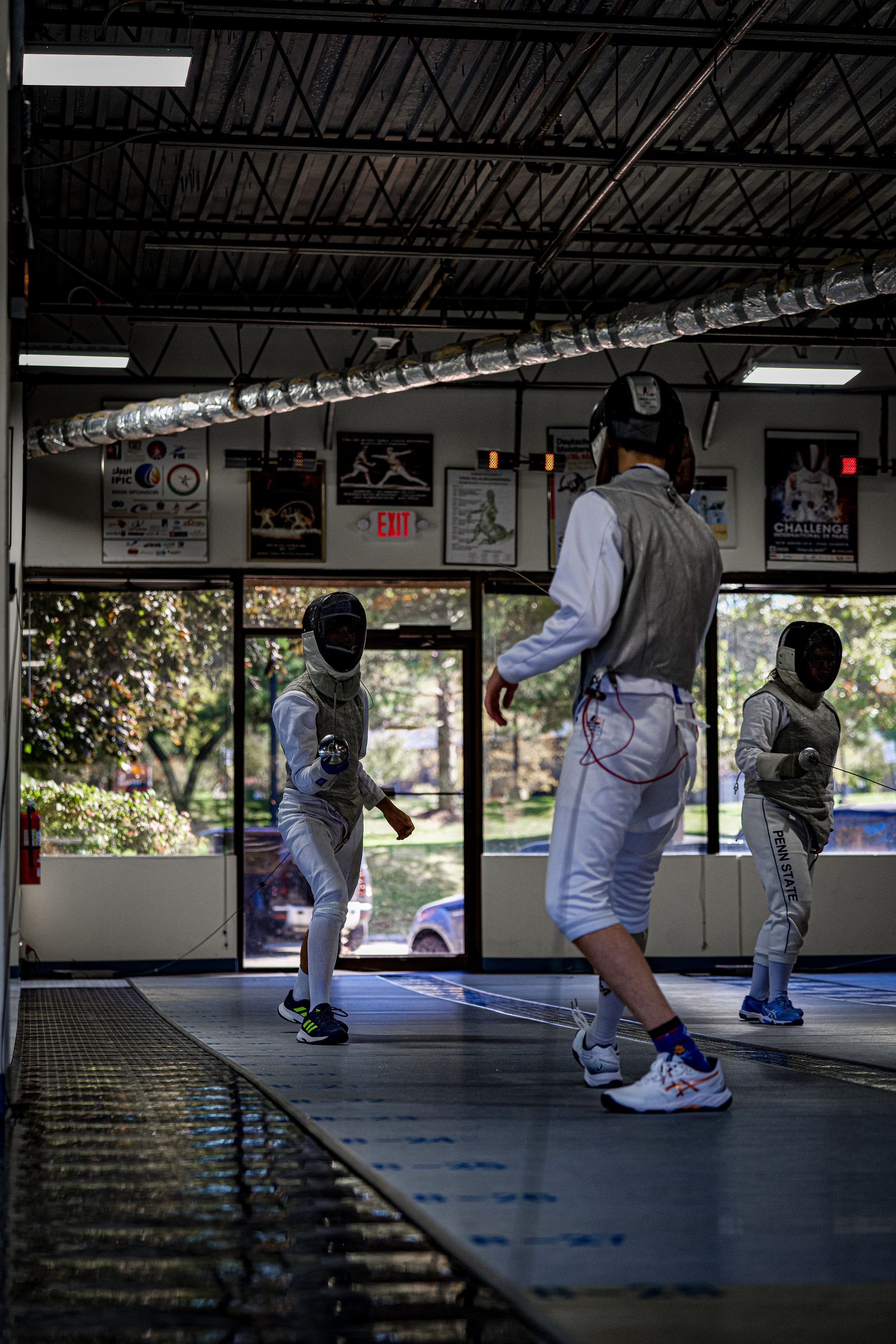 A group of young men are playing fencing in a gym.