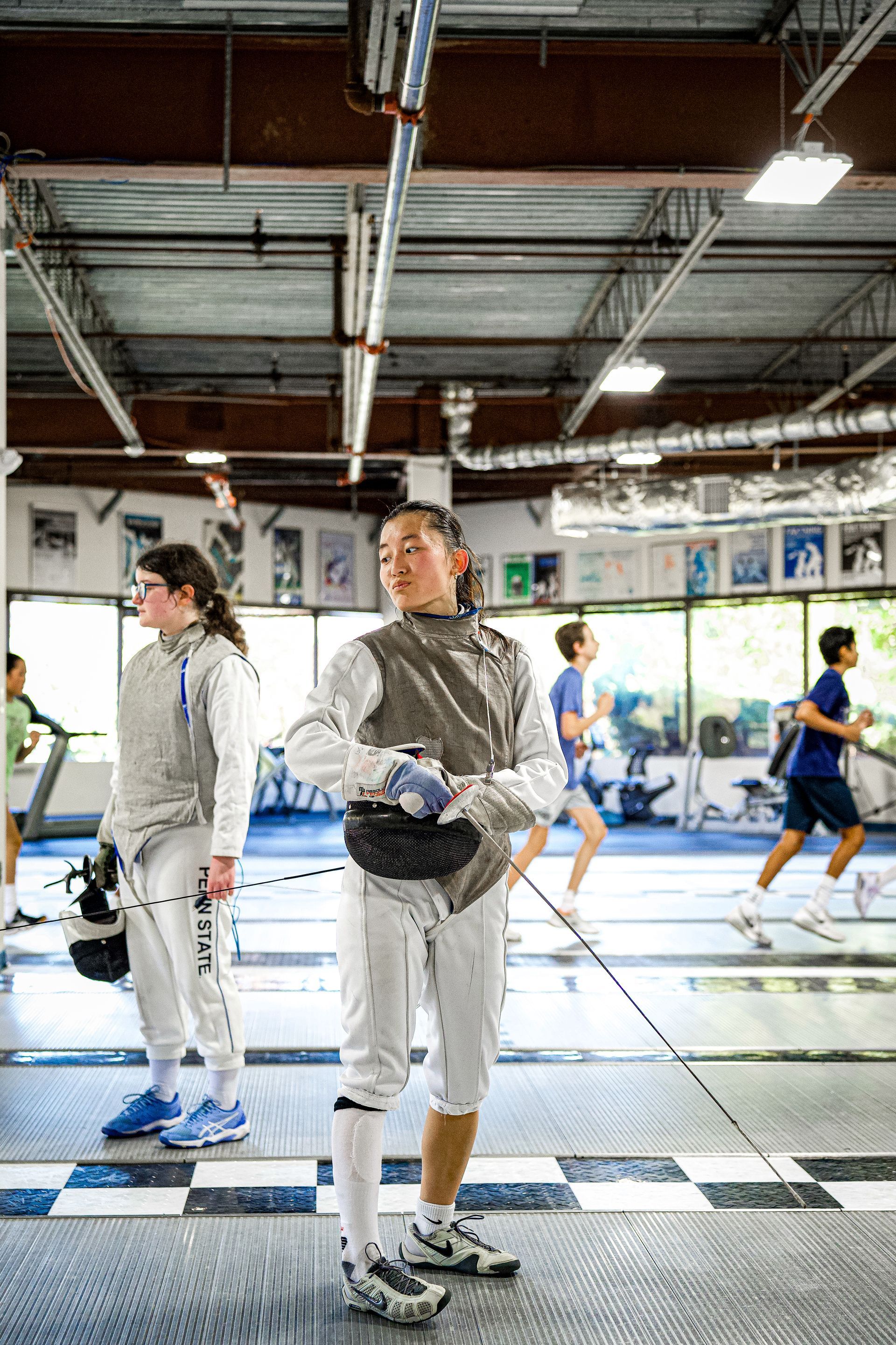 A group of people are practicing fencing in a gym.