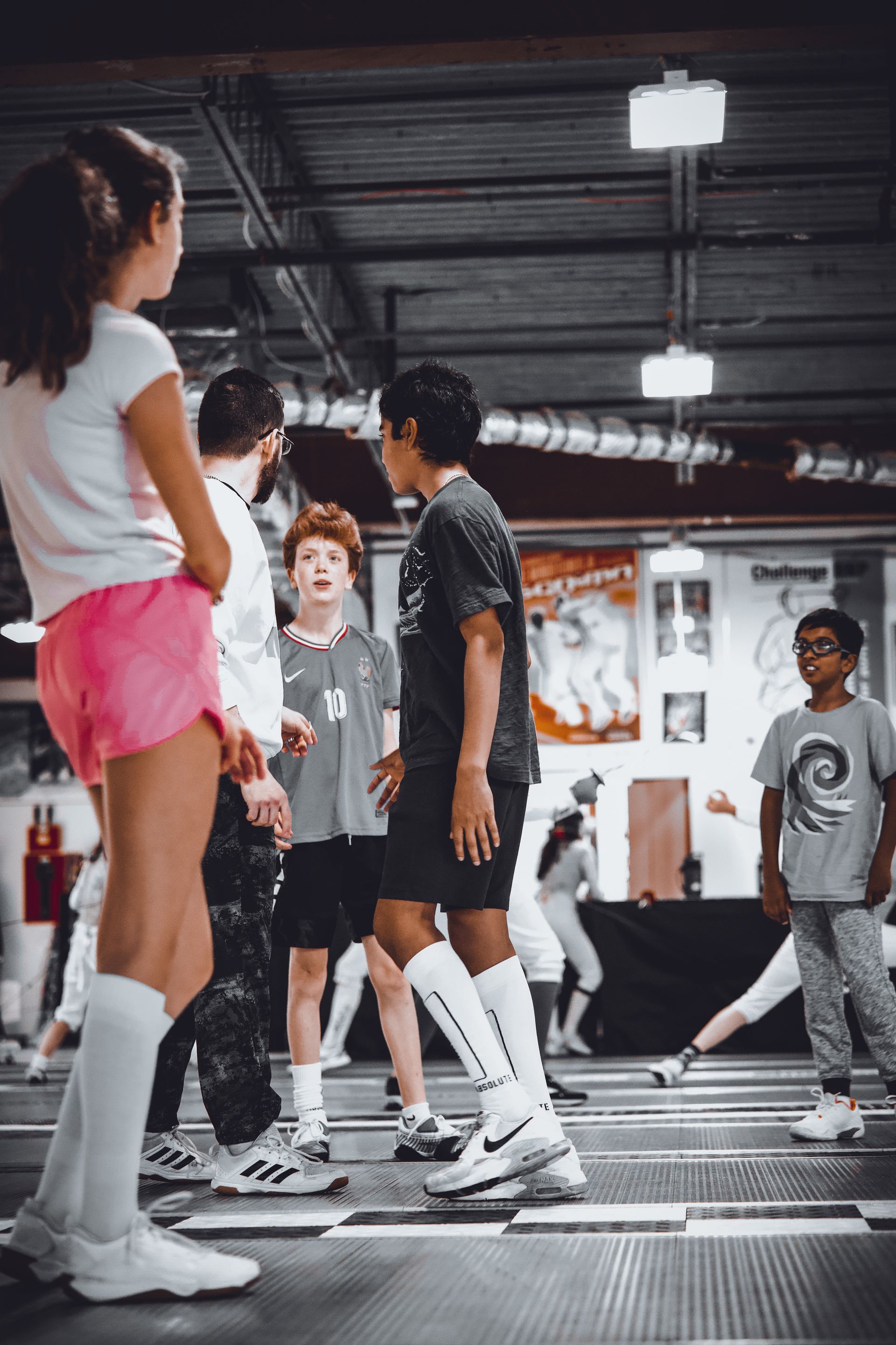 A group of children are standing in a gym talking to each other.