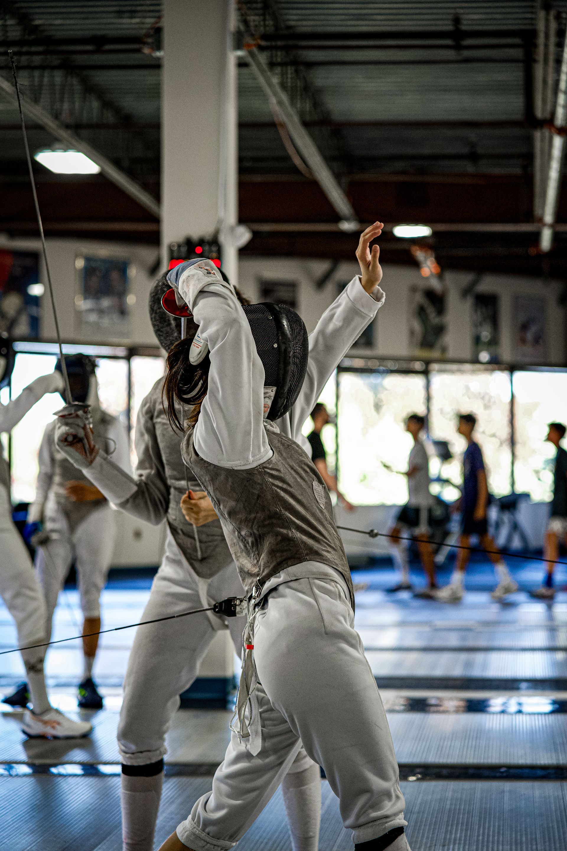 A group of people are playing fencing in a gym.