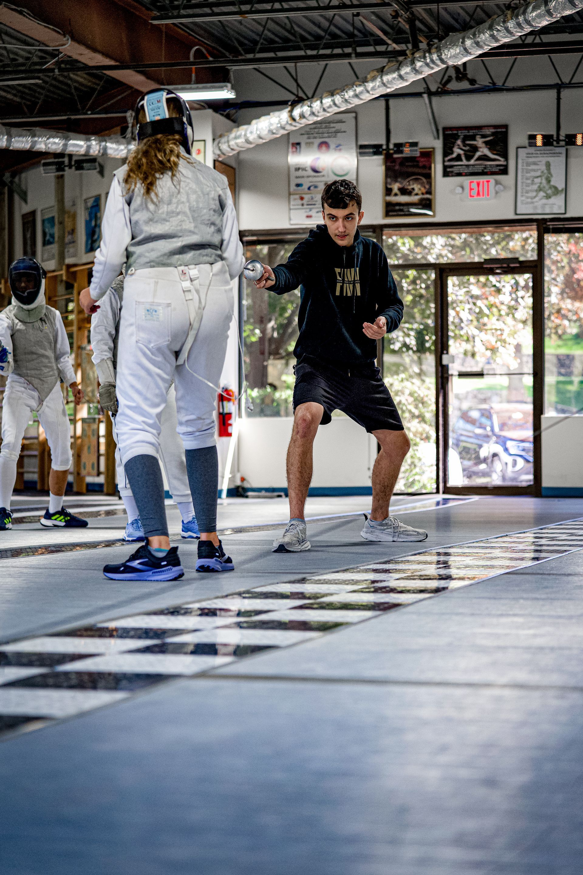 A group of people are practicing fencing in a gym.
