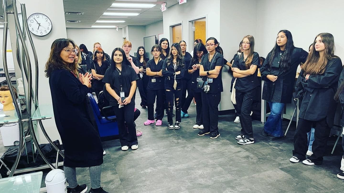 Group of people in black scrubs in a hallway, looking at someone off-camera.