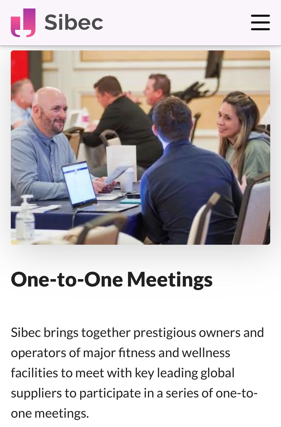 A group of people are sitting around a table with laptops.