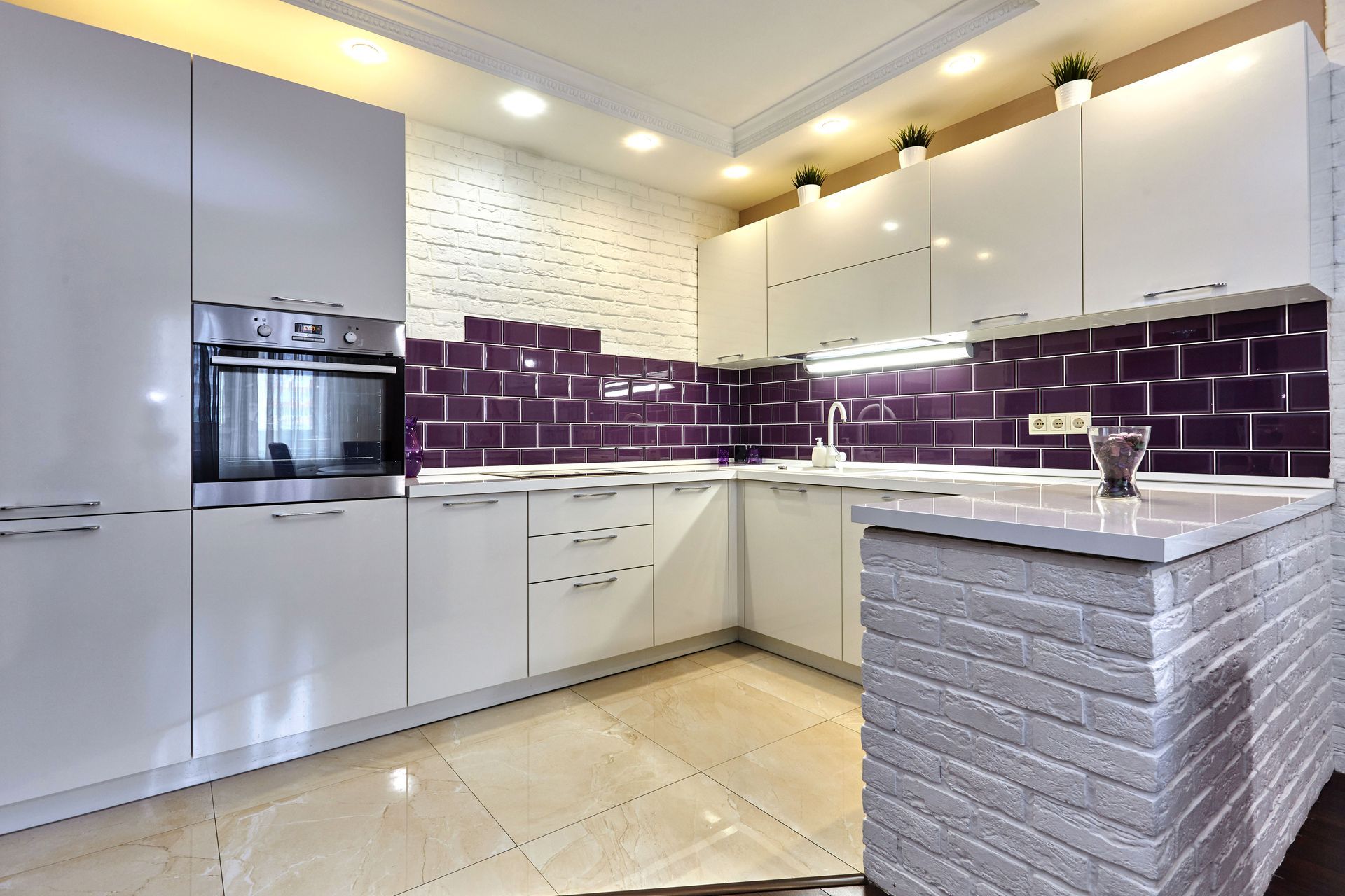 Modern kitchen with white cabinets, purple backsplash, and a brick island.