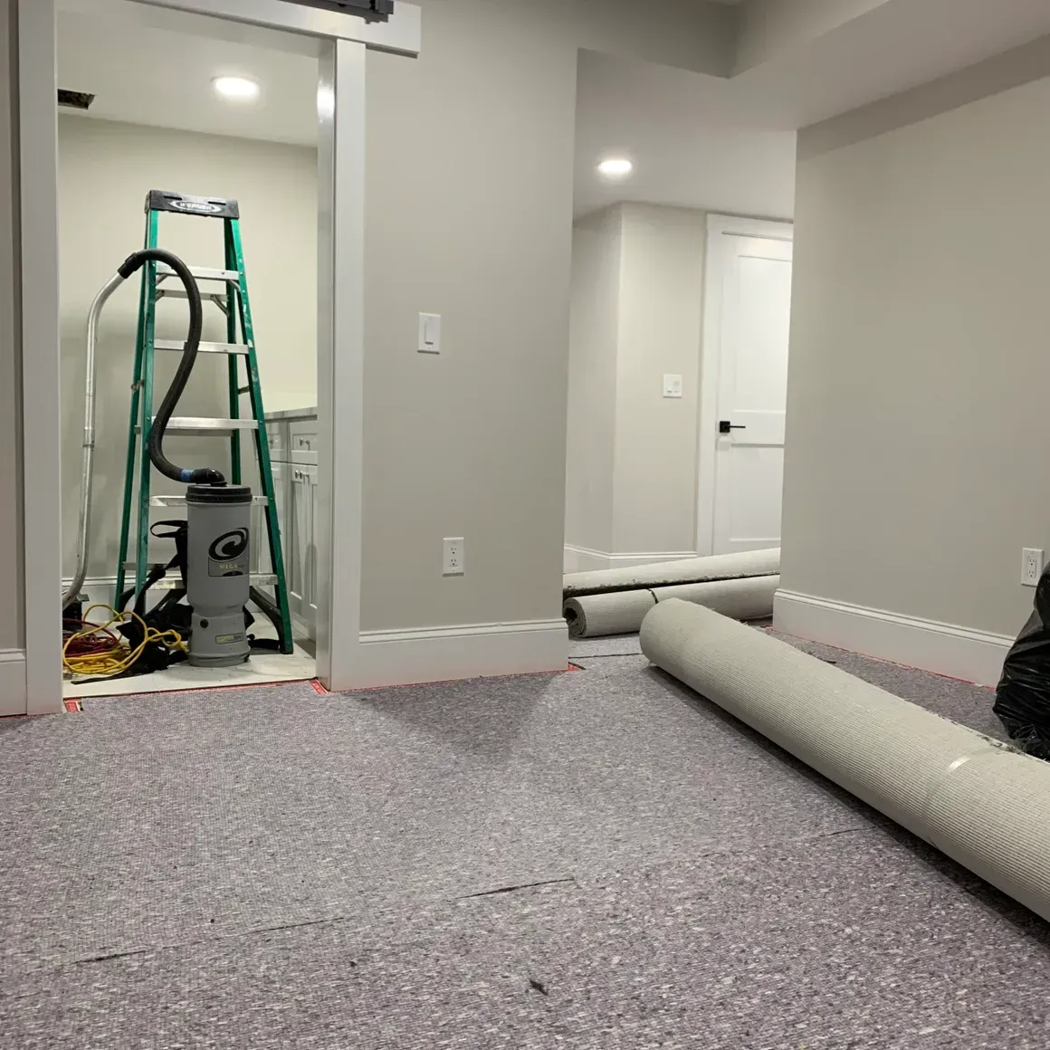 A room with a vacuum cleaner and a ladder in it