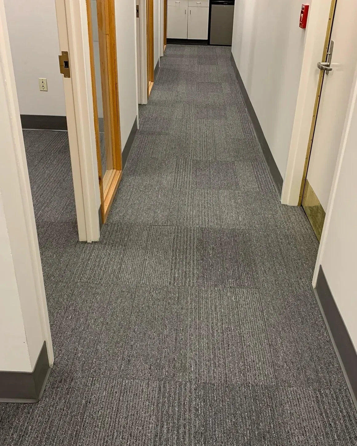 A long hallway with a gray carpet and white walls.